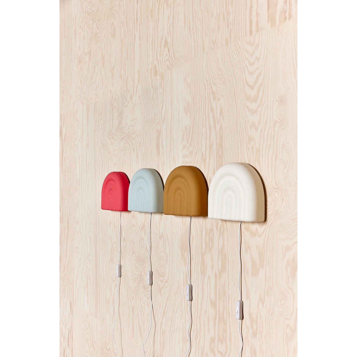 Witte siliconen wandlamp naast 3 andere siliconen wandlampen in verschillende kleuren