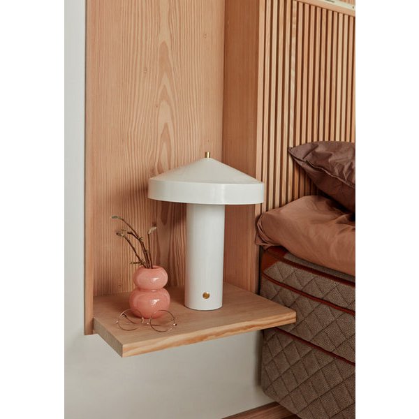 Witte tafellamp op een licht houten nachtkastje in een Scandinavisch interieur.