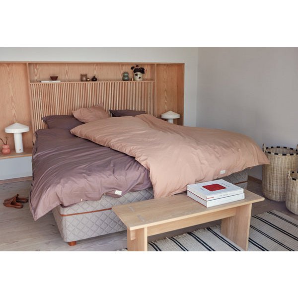 Witte tafellamp in een minimalistische slaapkamer met warme aardetinten en houten meubels.