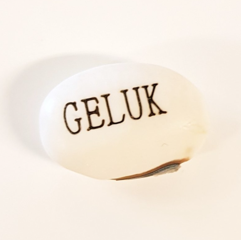 Witte wensboon met tekst GELUK gegraveerd op lichte achtergrond
