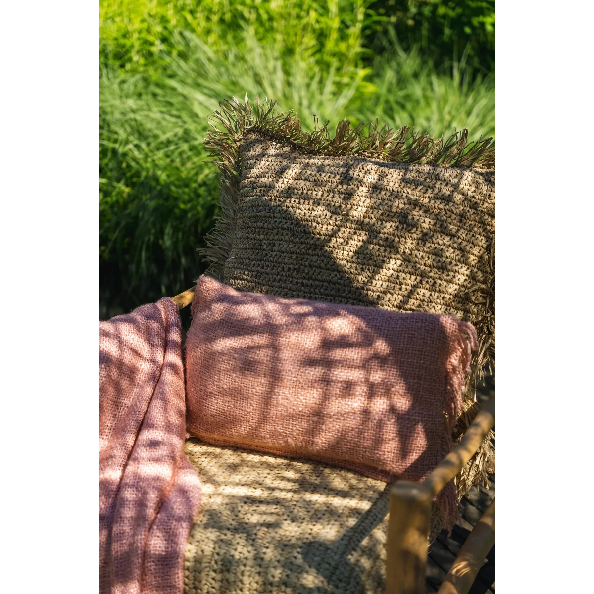 Zalmroze en bruin kussen in de zon op een buitenstoel