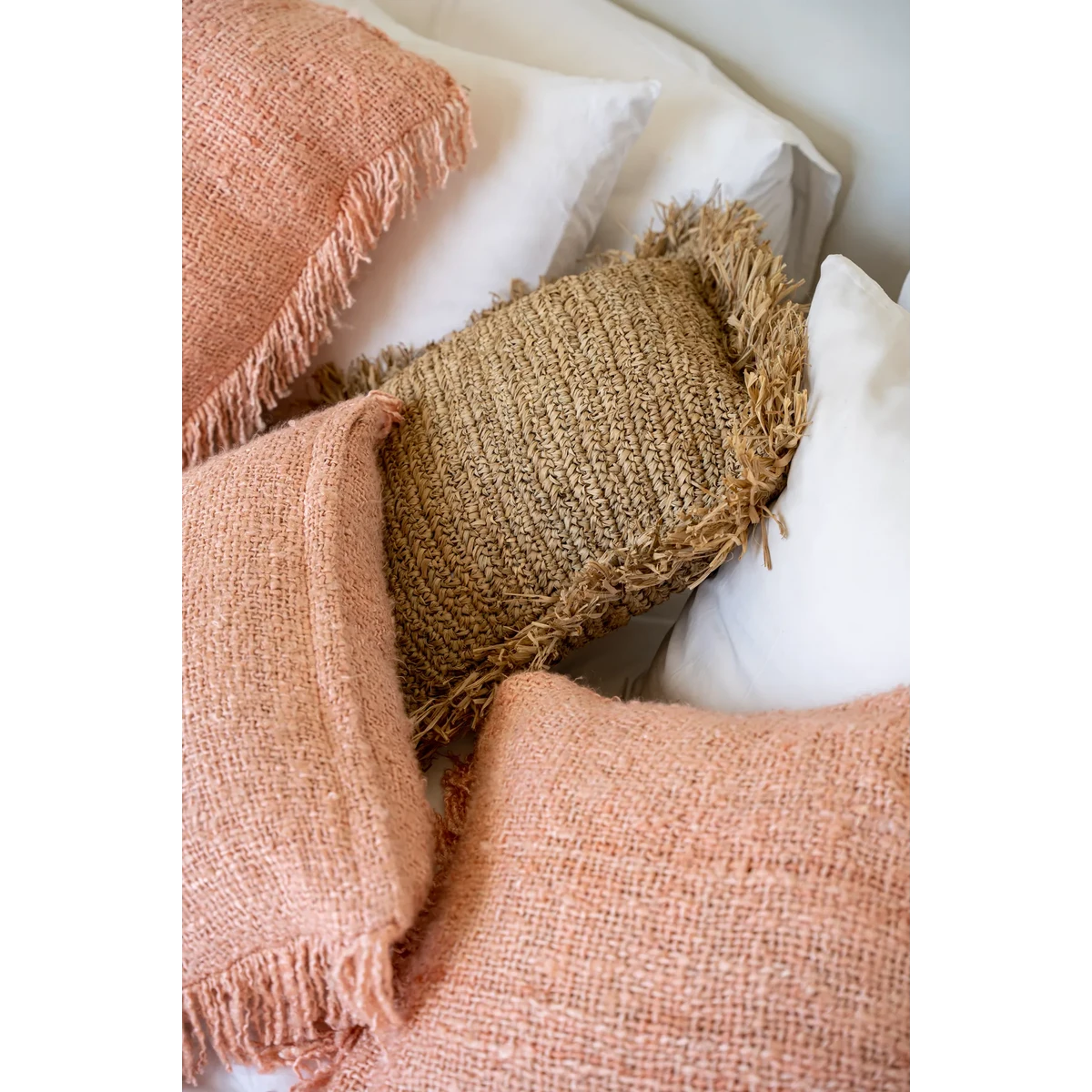 Zalmroze kussenhoes gecombineerd met bruin kussen op bed