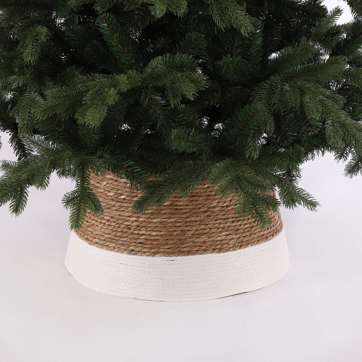 Rotan kerstboommand met witte basis – decoratieve afwerking die de kerstboomvoet elegant verbergt.
