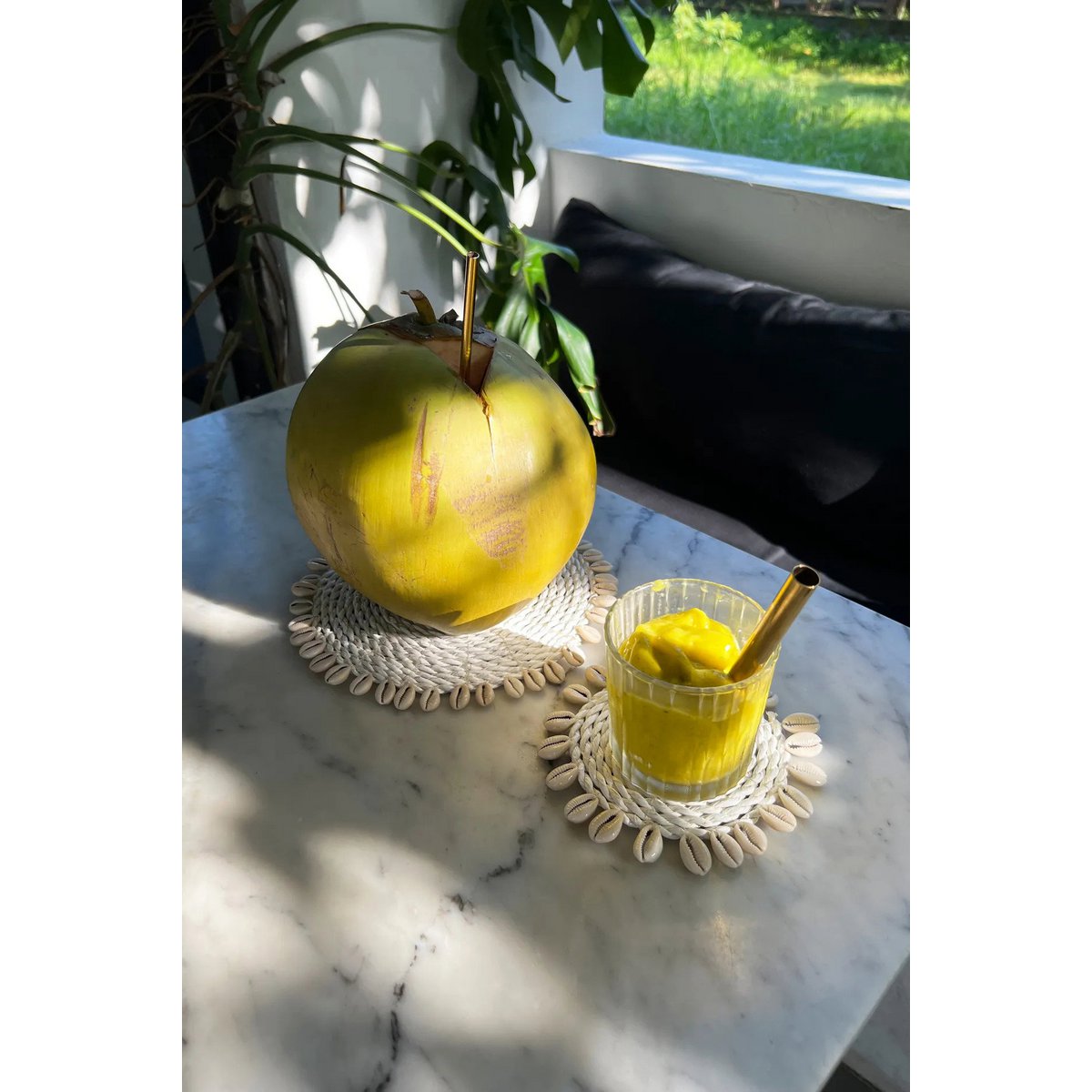 Zeegras onderzetter wit met schelpen 23 cm in een natuurlijke kamer met een kokosnoot en smoothie
