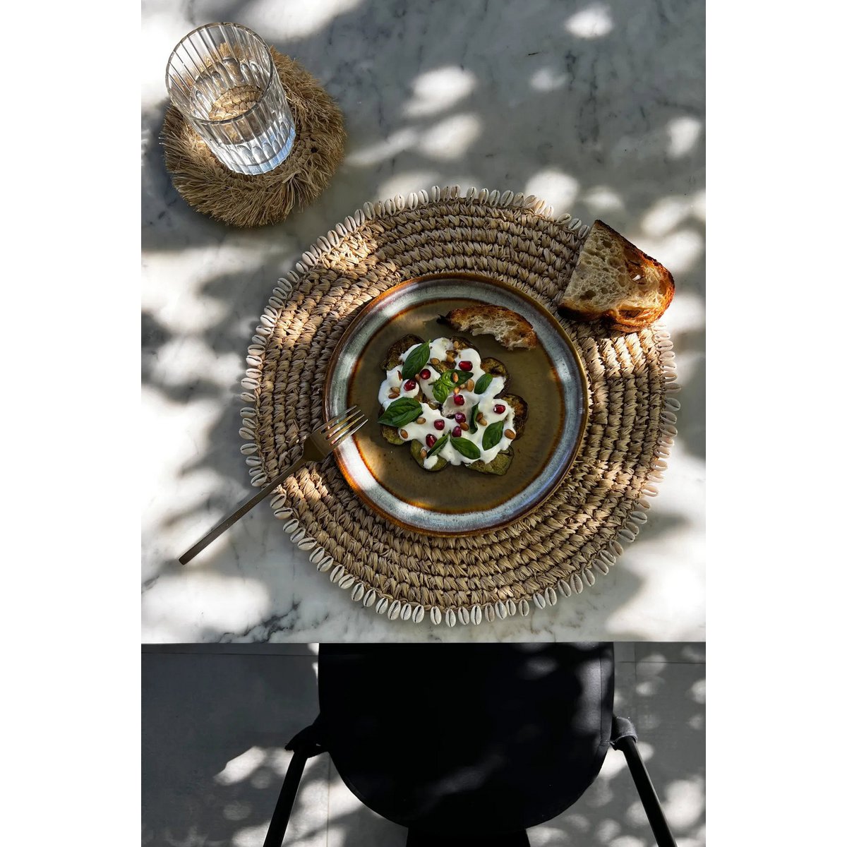 Zeegras placemat met schelpen naturel 38 cm buiten om tafel met daarop een bord met lekker eten van bovenaf