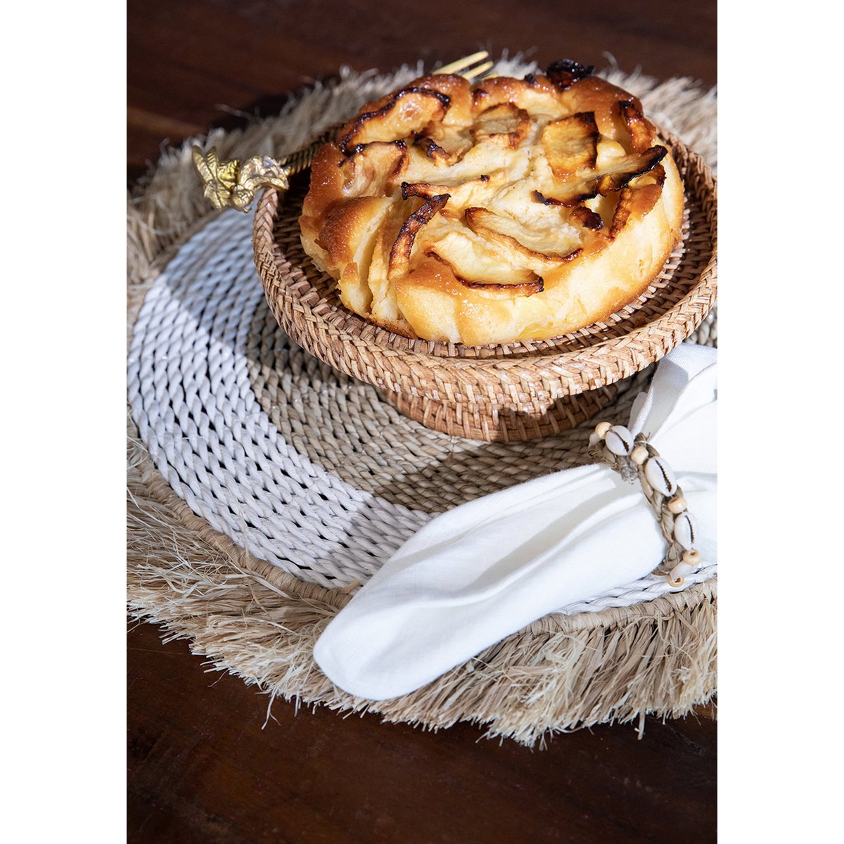 Zeegras raffia placemat naturel wit 45 cm met daarop een gevlochten schaal met een taart erop