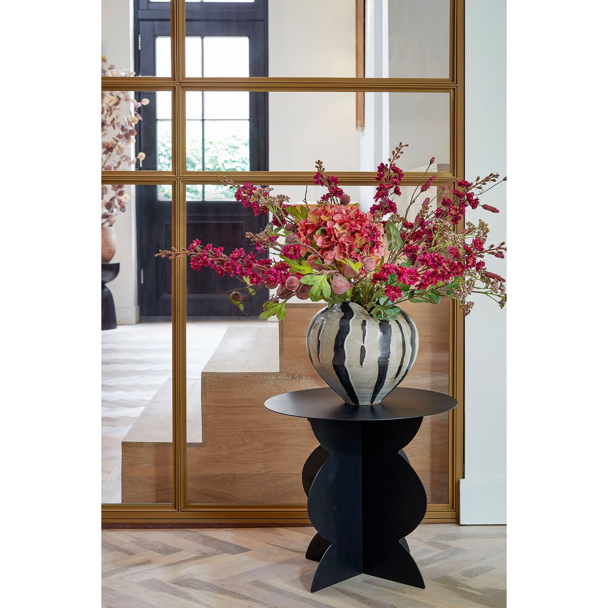 Zwarte ijzeren bijzettafel Rafi in modern interieur, met een vaas met bloemen