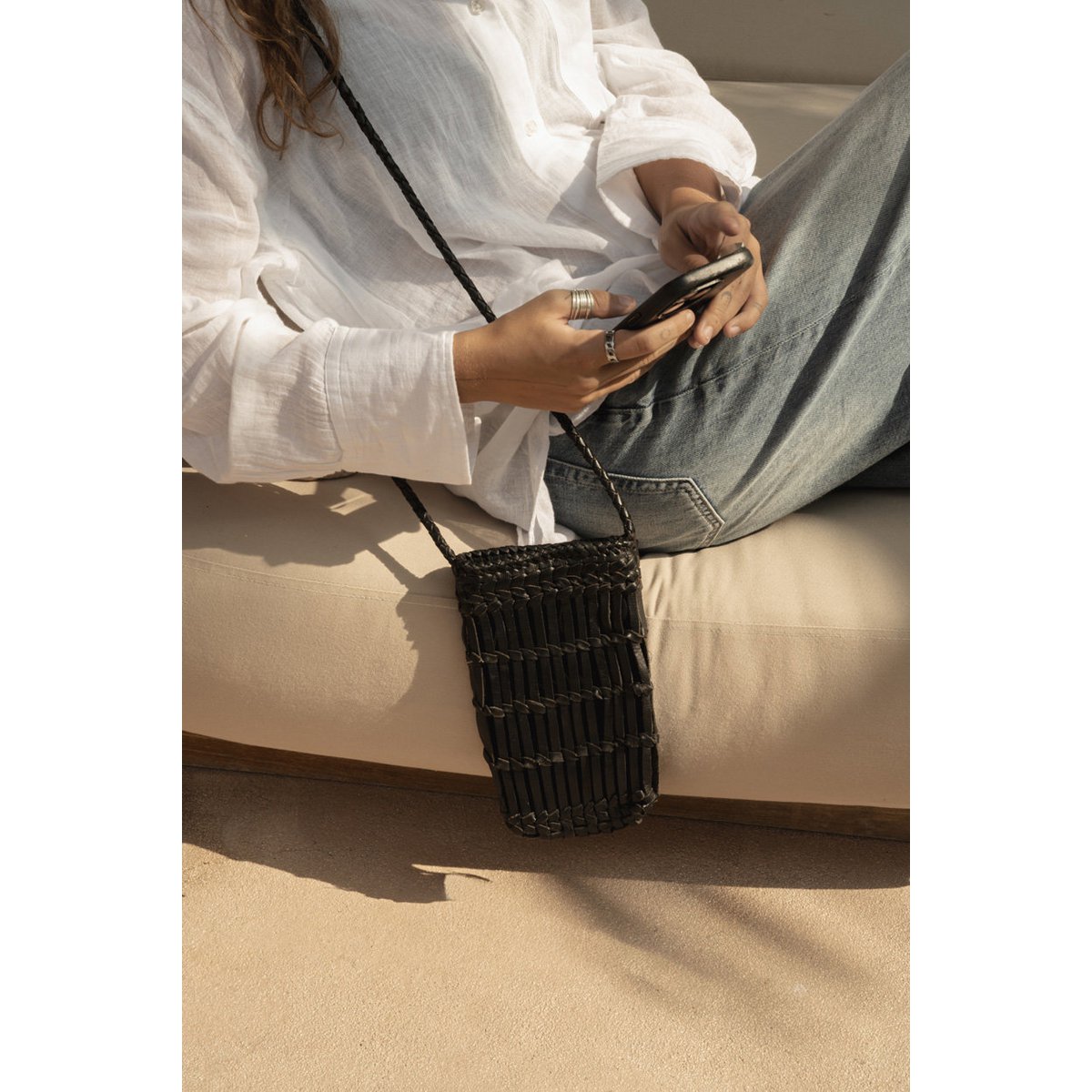 Telefoontas gedragen door model over de schouder in een casual setting