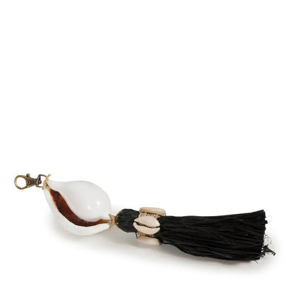 Zwarte raffia sleutelhanger met schelp liggend op tafel