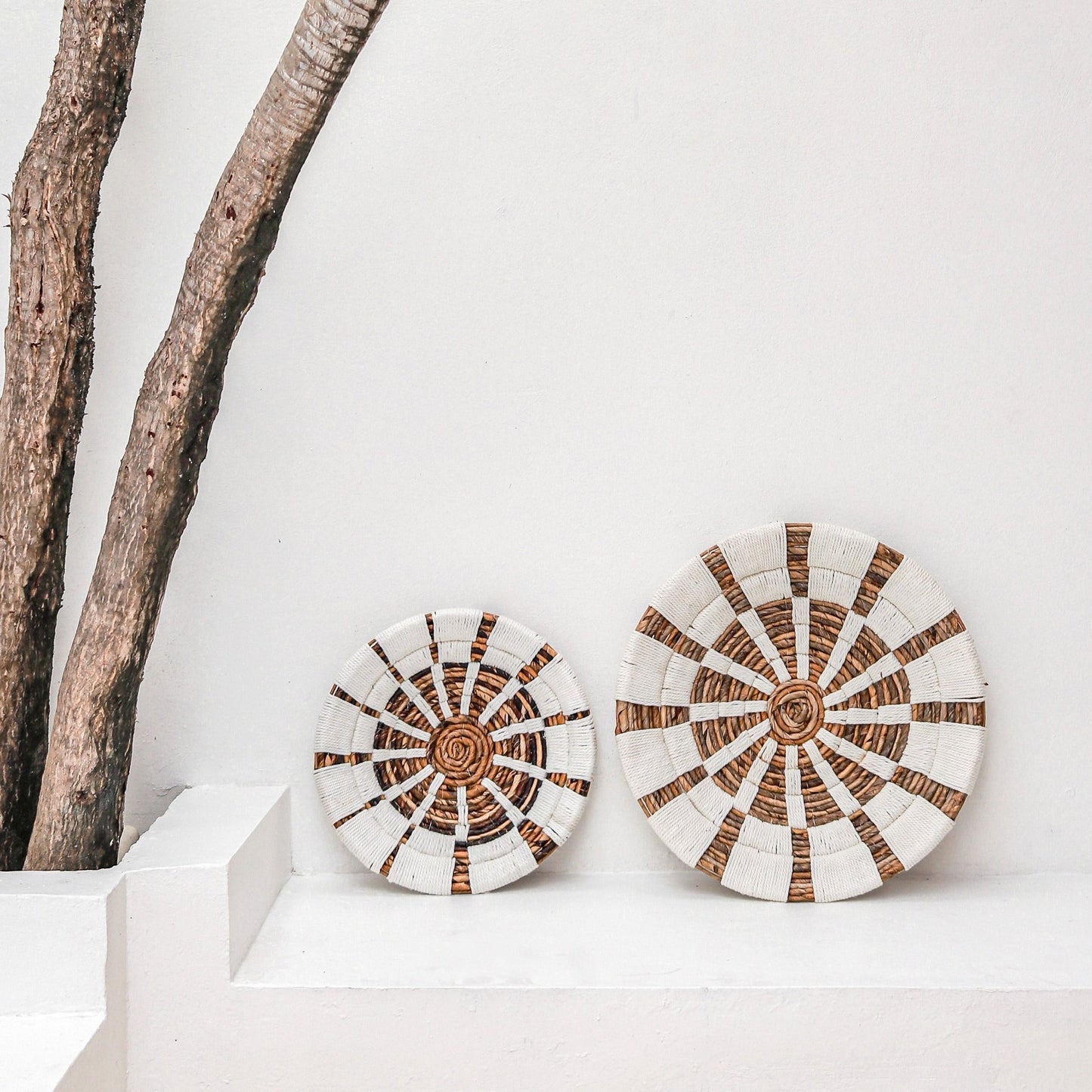 Boho muurdecoratie naast elkaar naast boom, op witte bank