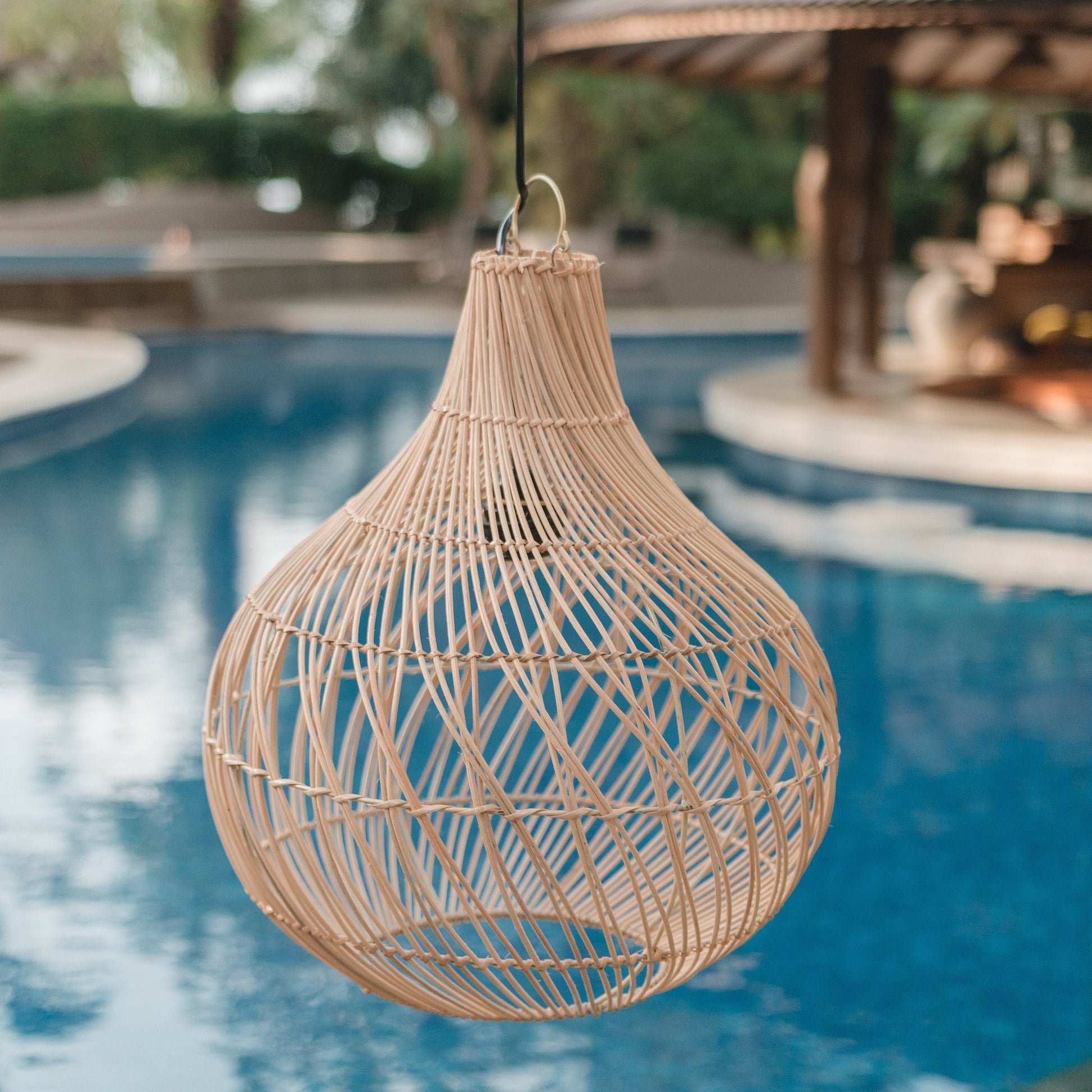 Rotan hanglamp Kenari met op de achtergrond een zwembad. Perfect voor een boho of Ibiza lifestyle.