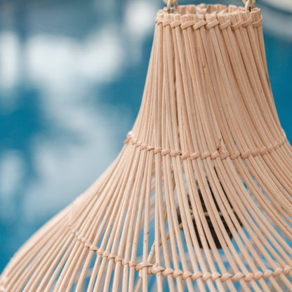 Closeup detail foto van de Rotan hanglamp Kenari, met op de achtergrond water. Perfect voor een boho of Ibiza lifestyle.