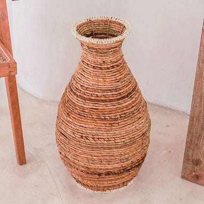 Sier vaas Tumbak bananenvezel en raffia naast andere meubels zoals houten stoelen en kasten