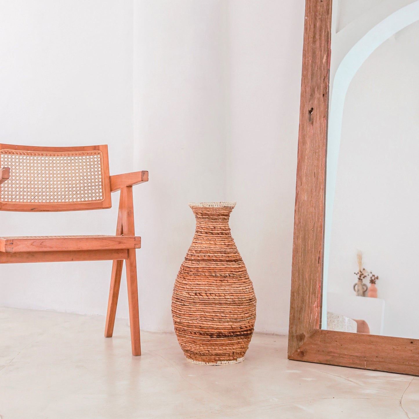 Sier vaas Tumbak bananenvezel en raffia naast een boho stoel en Ibiza spiegel