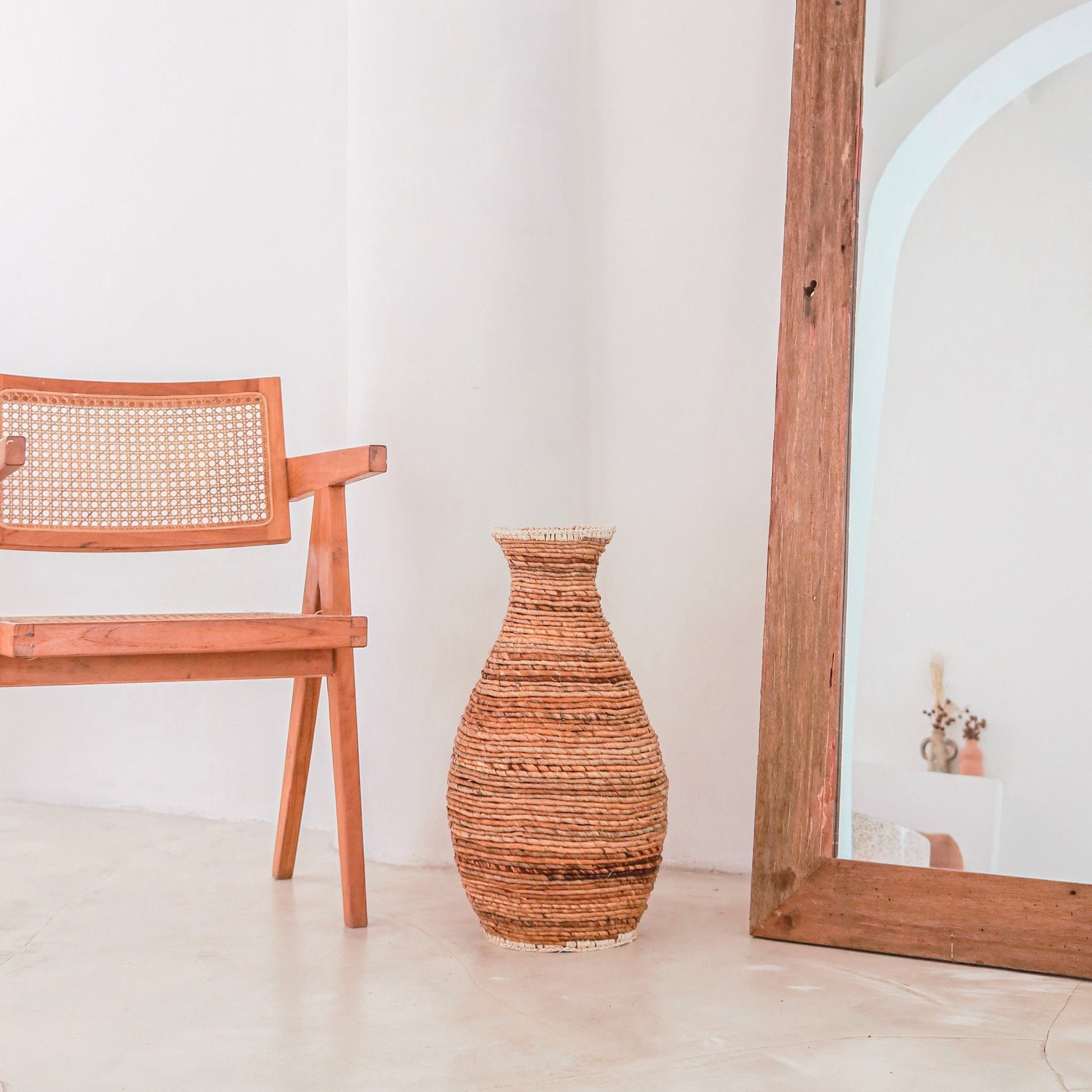 Sier vaas Tumbak bananenvezel en raffia naast een boho stoel en Ibiza spiegel