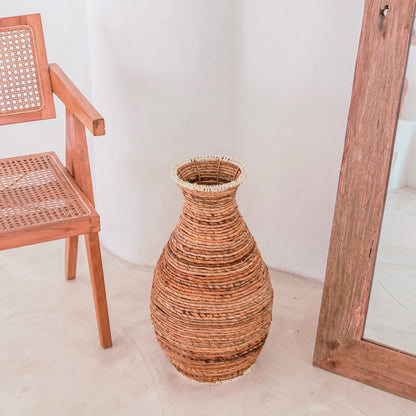 Sier vaas Tumbak bananenvezel en raffia van bovenaf genomen naast een boho stoel een Ibiza spiegel