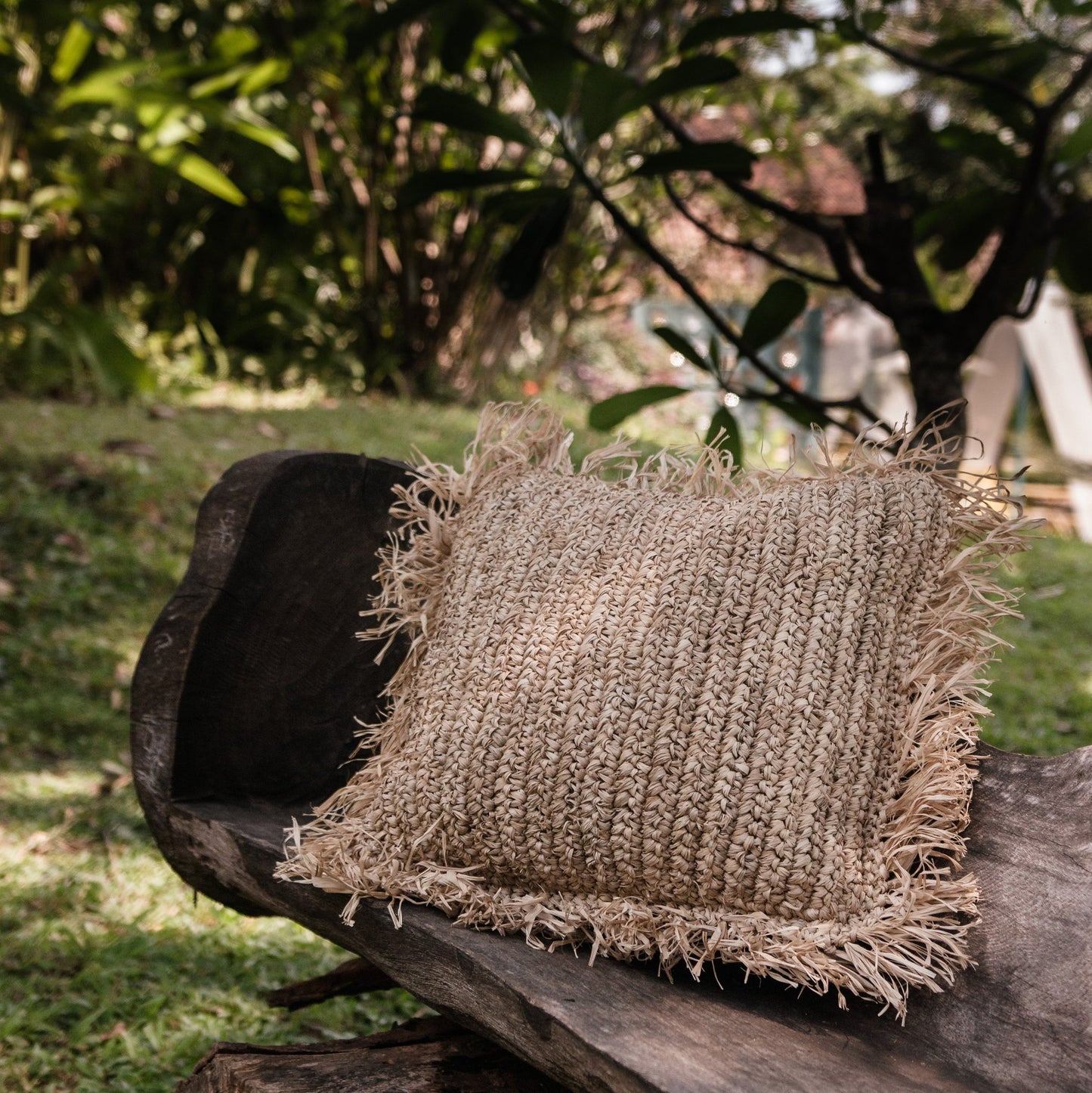 Sierkussen raffia met franjes Gandi op een bankje buiten in de natuur
